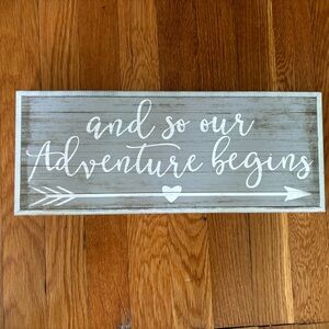 “And so our adventure begins” wooden sign
